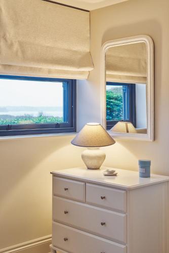 a bedroom with a dresser with a lamp and a mirror at Ty Alice in Oxwich