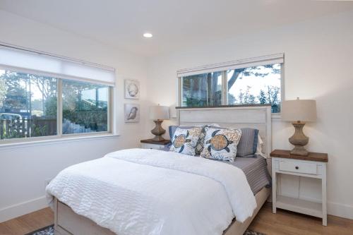 a white bedroom with a bed and two windows at Oceanfront Home Retreat w Breathtaking Views of Fitzgerald Marine Reserve in Moss Beach