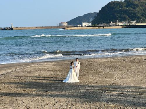 a bride and groom standing on the beach at Shirahama in Miyazaki