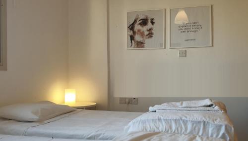 1 dormitorio con 1 cama blanca y 2 cuadros en la pared en ELLA LUXURY APARTMENT - (BREAKBOOKING CY) en Limassol