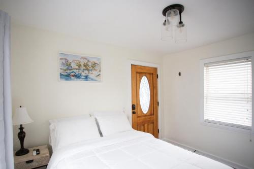 a white bedroom with a bed and a window at Cozy Studio - Blocks from the Ocean! in Jacksonville Beach