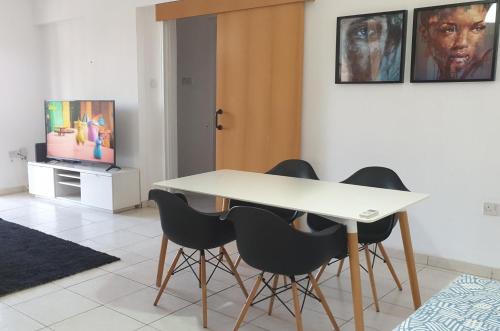 a dining room with a white table and black chairs at ELLA LUXURY APARTMENT - (BREAKBOOKING CY) in Limassol