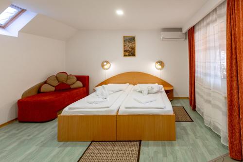 1 dormitorio con 1 cama y 1 sofá rojo en Pensiunea Joker en Sighişoara