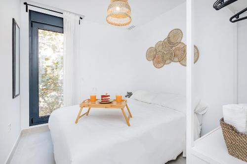 Un dormitorio blanco con una mesa en una cama en BHost - Waikiki, en Tarifa