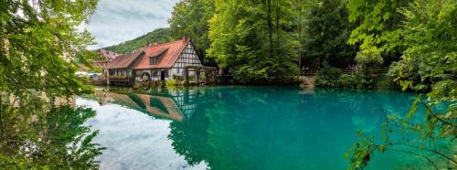 a house in the middle of a river with blue water at Abbate Boutique Hotel in Ulm