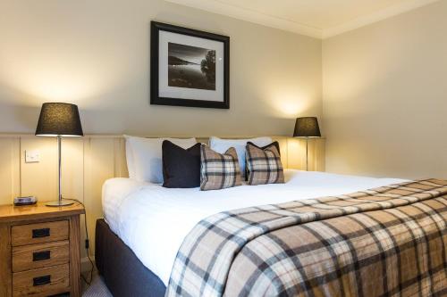 a bedroom with a large bed and two lamps at Cameron House Lodges in Balloch