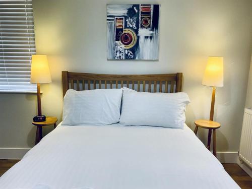 ein Schlafzimmer mit einem großen weißen Bett mit zwei Lampen in der Unterkunft Cloud9StayZ at The Oakridge in Woking