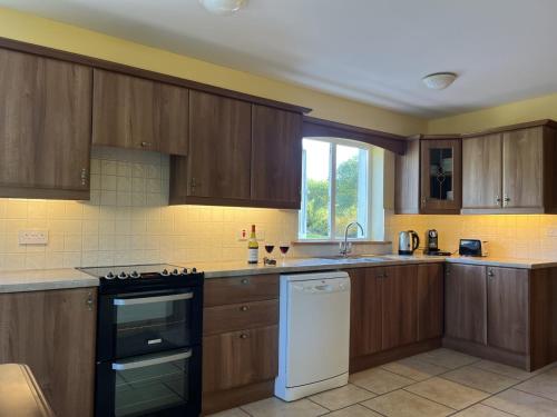a kitchen with wooden cabinets and a stove top oven at Valentia View Holiday Home by Trident Holiday Homes in Cahersiveen