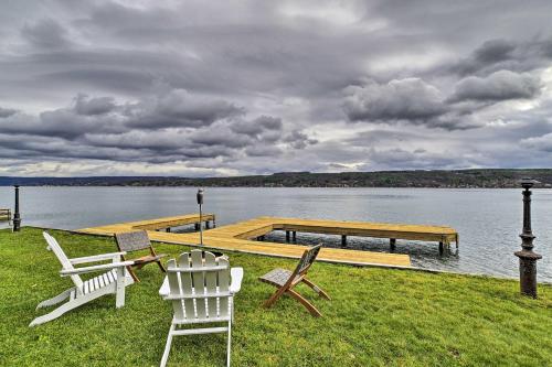a group of chairs sitting on the grass next to a dock at Charming Home on Keuka Lake with Dock and Fire Pit! in Hammondsport