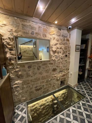 a large mirror on a stone wall with a swimming pool at VIRSA BOUTIQUE ROOMS in Ioannina