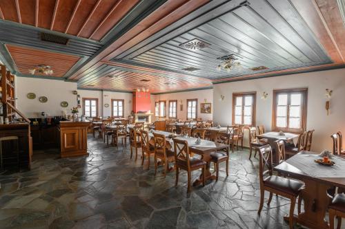 um restaurante com mesas e cadeiras de madeira e janelas em Papigiotis Hotel em Tsepelovo