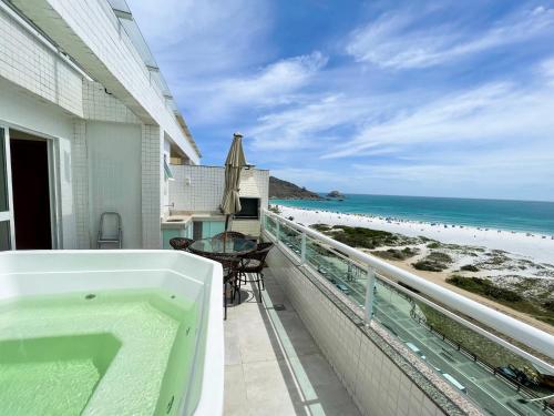 a bath tub on a balcony with a view of the beach at Cobertura Luxo com Jacuzzi Orla Praia Grande in Arraial do Cabo