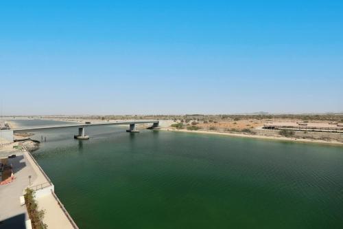 a bridge over a river with green water at Yas Island - 2 Bedrooms, 2 toilet with shared Pool & Parking in Abu Dhabi
