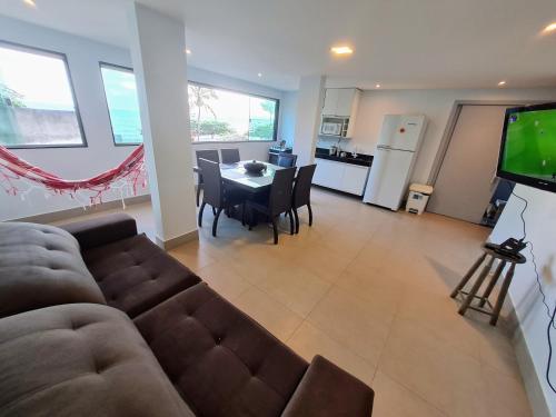 a living room with a couch and a table and a television at Apt FRENTE MAR MEAIPE COMPLETO in Guarapari