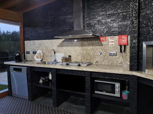 una cocina con fregadero y microondas en Refúgio, en Castelo de Paiva