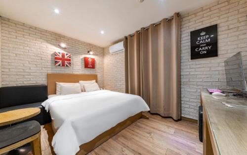 a bedroom with a large white bed and a desk at Laria Hotel in Suwon