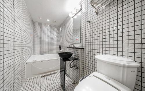 a bathroom with a toilet and a sink and a tub at Laria Hotel in Suwon