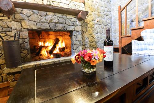 a bottle of wine and flowers on a table with a fireplace at Pera Alonia Guest House in Kato Trikala Korinthias