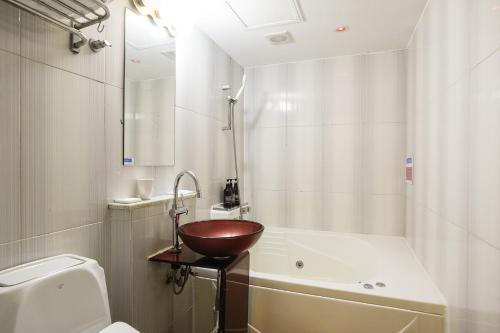 a bathroom with a bowl sink next to a bath tub at Laria Hotel in Suwon