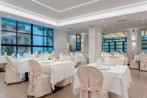 un salón de banquetes con mesas y sillas blancas en Hotel Queen Mary, en Cattolica