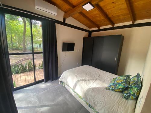 a bedroom with a bed and a large window at Vila Uluwatu 1 in Florianópolis