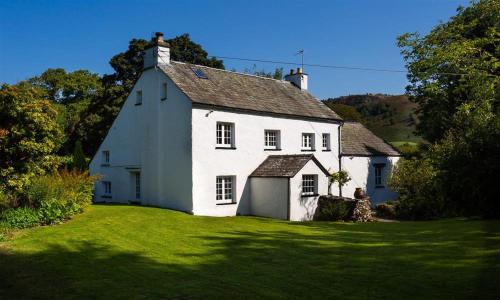 a white house sitting on a green lawn at Fair Rigg Old Farm in Cartmel