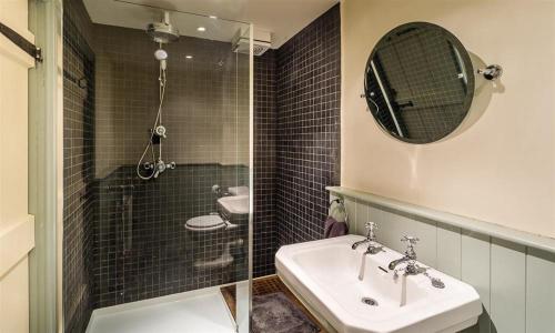 a bathroom with a sink and a shower and a mirror at Thimble Hall in Grasmere