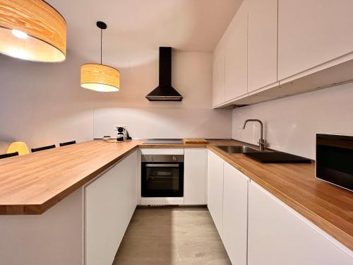 a kitchen with white cabinets and a wooden counter top at Housingleón - Palacio de Don Ramiro in León