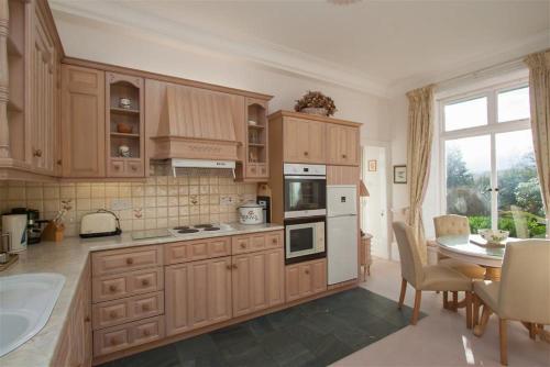 cocina con armarios de madera, mesa y comedor en Betamere, en Ambleside