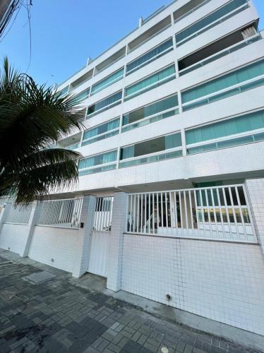 a white building with a palm tree in front of it at Cobertura Luxo com Jacuzzi Orla Praia Grande in Arraial do Cabo