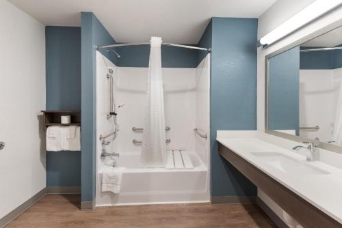a bathroom with a shower and a tub and a sink at WoodSpring Suites Dayton North in Dayton