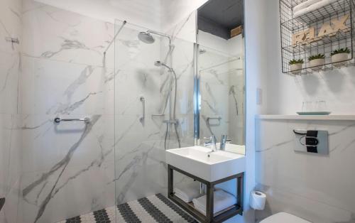 a white bathroom with a shower and a sink at Hotel67 in Killarney