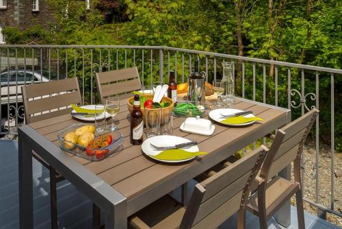 a wooden table with food and drinks on a balcony at Riverville in Grasmere
