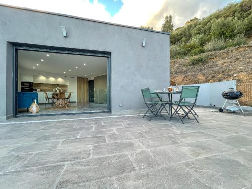 un patio avec une table et des chaises à côté d'un bâtiment dans l'établissement Villa L'Alba BASTIA, à Bastia