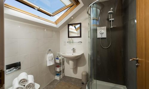 uma casa de banho com uma cabina de duche em vidro e um lavatório. em Bowderstone em Keswick