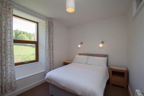a bedroom with a white bed and a window at Robins Nest in Coniston