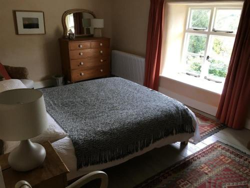um quarto com uma cama, uma cómoda e uma janela em Thomas Cottage em Penrith
