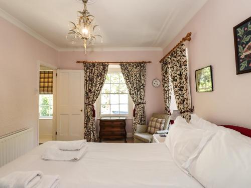 a bedroom with a large white bed with a chandelier at Jessicas Cottage in Bowness-on-Windermere