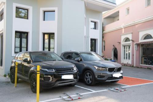two cars parked in a parking lot in front of a building at COCO SUITES in Vasiliki