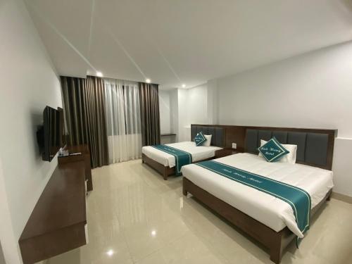 une chambre d'hôtel avec deux lits et une télévision à écran plat dans l'établissement Minh Hưng Motel, à Hạ Long
