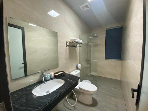 une salle de bain avec un lavabo, des toilettes et un miroir dans l'établissement Minh Hưng Motel, à Hạ Long