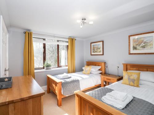 a bedroom with two beds and a table and a desk at Spring Cottage in Ambleside