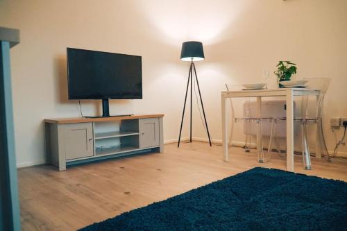 a living room with a flat screen tv on a stand with a table at Modern 2 Bed Apartment Near City Centre in Chelmsford