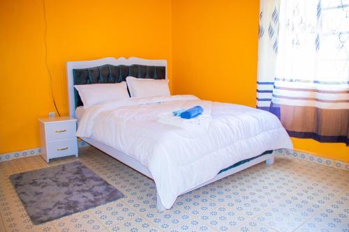 a yellow bedroom with a bed with a blue phone on it at Secure Standalone 3BR Home near Embu Uni and KSG in Embu