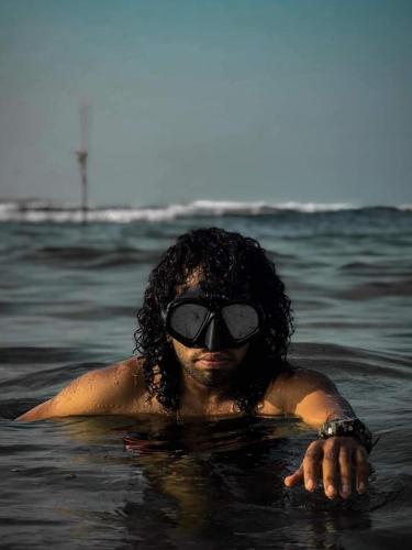 a woman in the water with sunglasses on at Indika's Apartment in Hikkaduwa