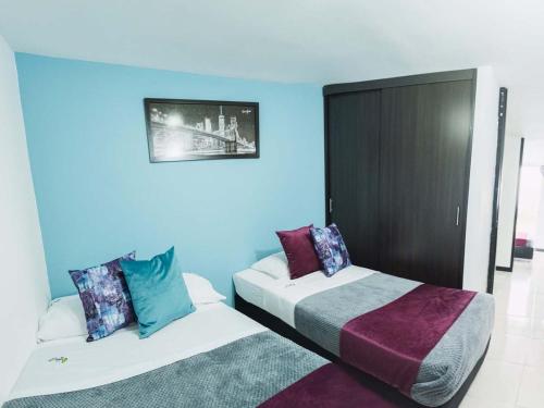 two beds in a room with blue walls at Apartamento Eje Cafetero a 2 km Parque del Café in Montenegro