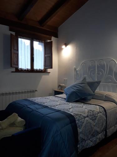 a bedroom with a bed with blue sheets and two windows at Casa Matilde in Proaza