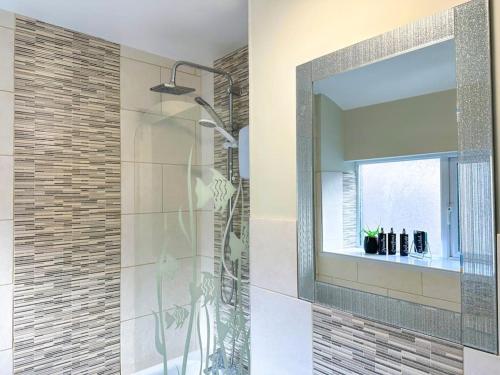 uma casa de banho com um chuveiro e um espelho grande em On Trend 3 Bedroom Home In Maerdy near Attractions 