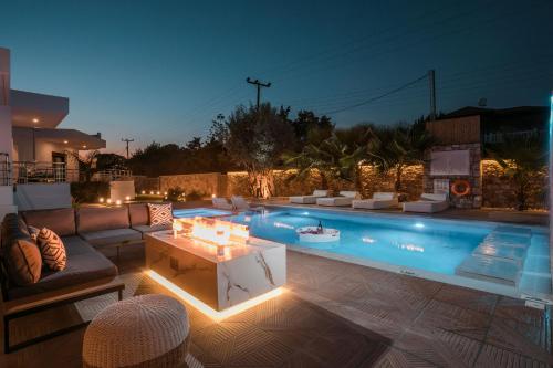 una piscina con divano e tavolo con luci di Le Ialyse Luxury Villa a Ialyssos