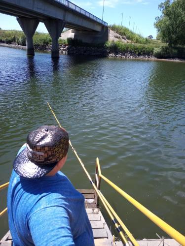 een man met een hoed roeit een boot op het water bij La rivera in Necochea